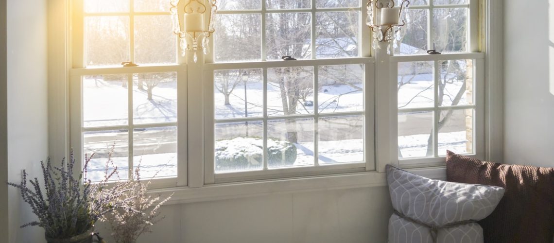 Photo taken inside a home showing a glass window . Snow and winter scene on outside.